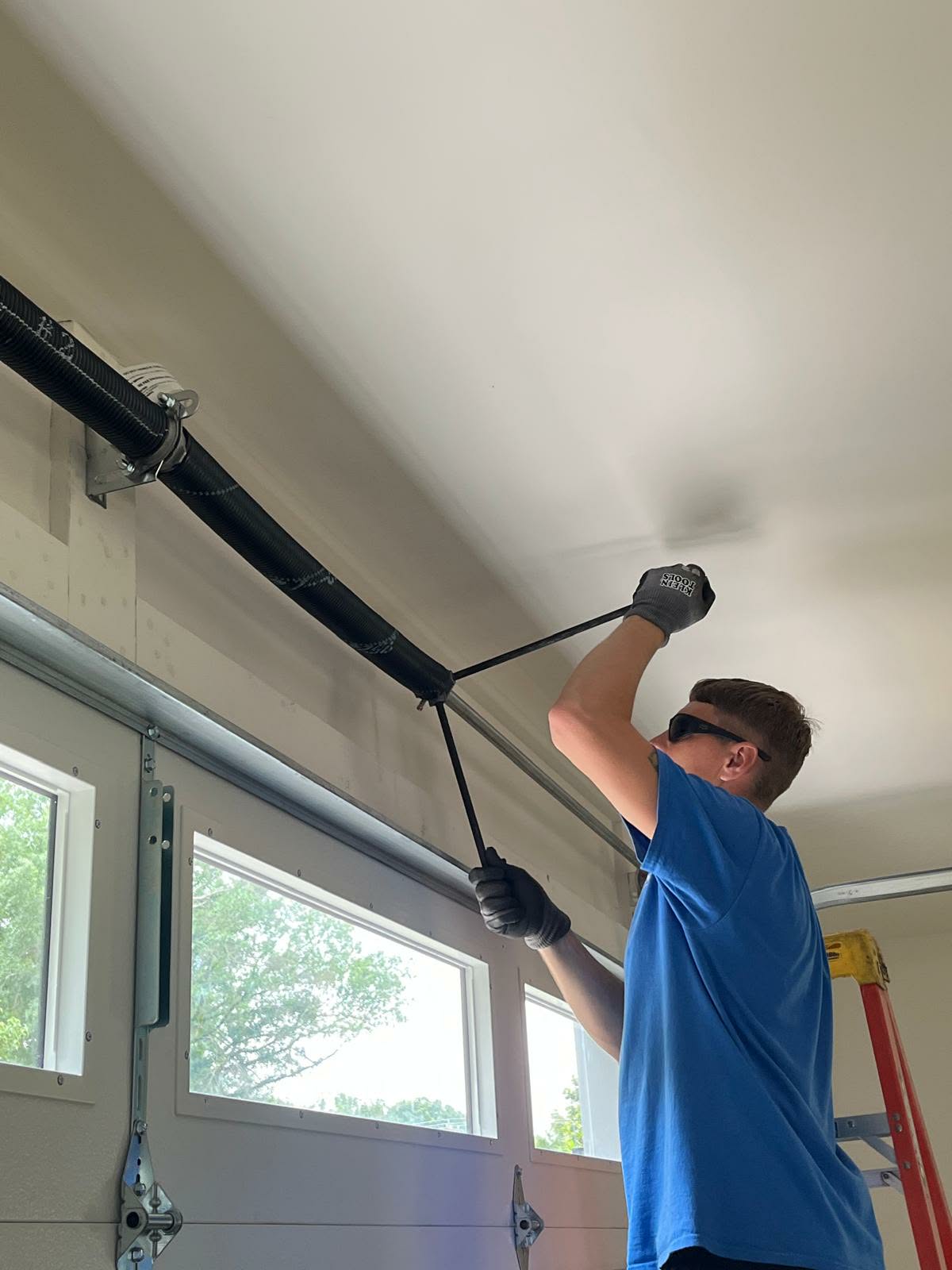 Ruslan tightening a torsion spring above a garage door